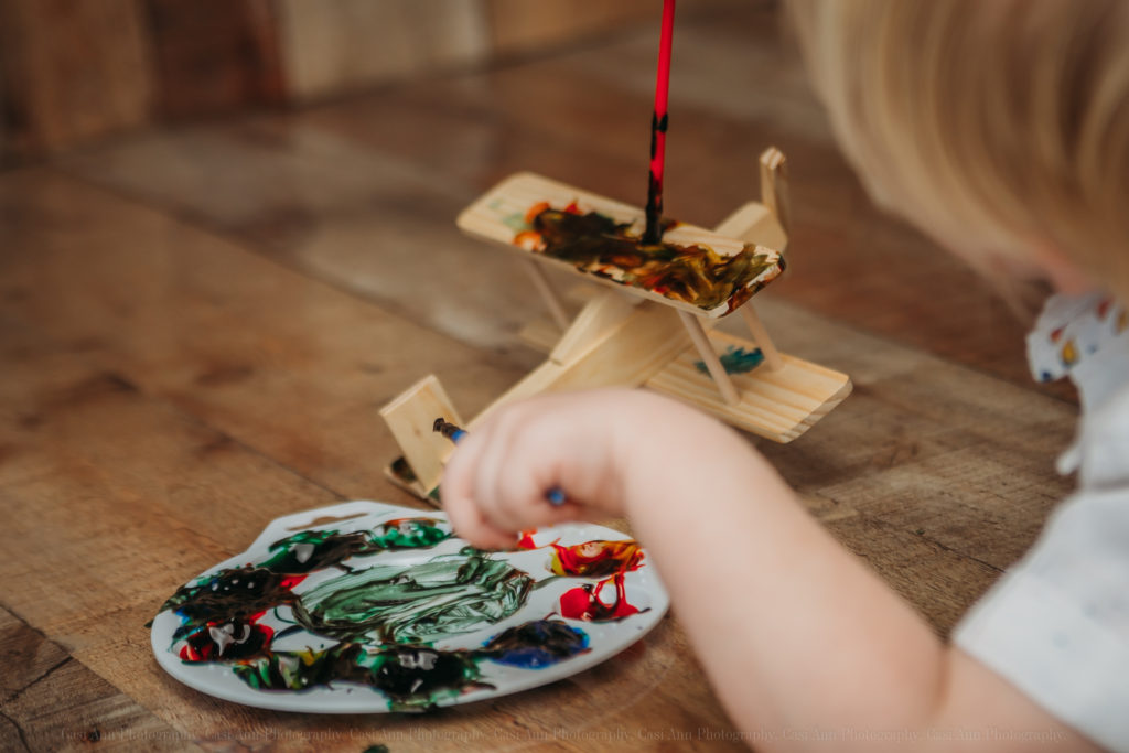 Toddler Lifestyle Photography-Casi Ann Photography-Illinois-IL-Ingleside-Lake County-Airplane-World Art Day-Arts-Crafts-Painting-Toddlers-Crafty-Photographer-Wood-Plane-Painted-studio-session