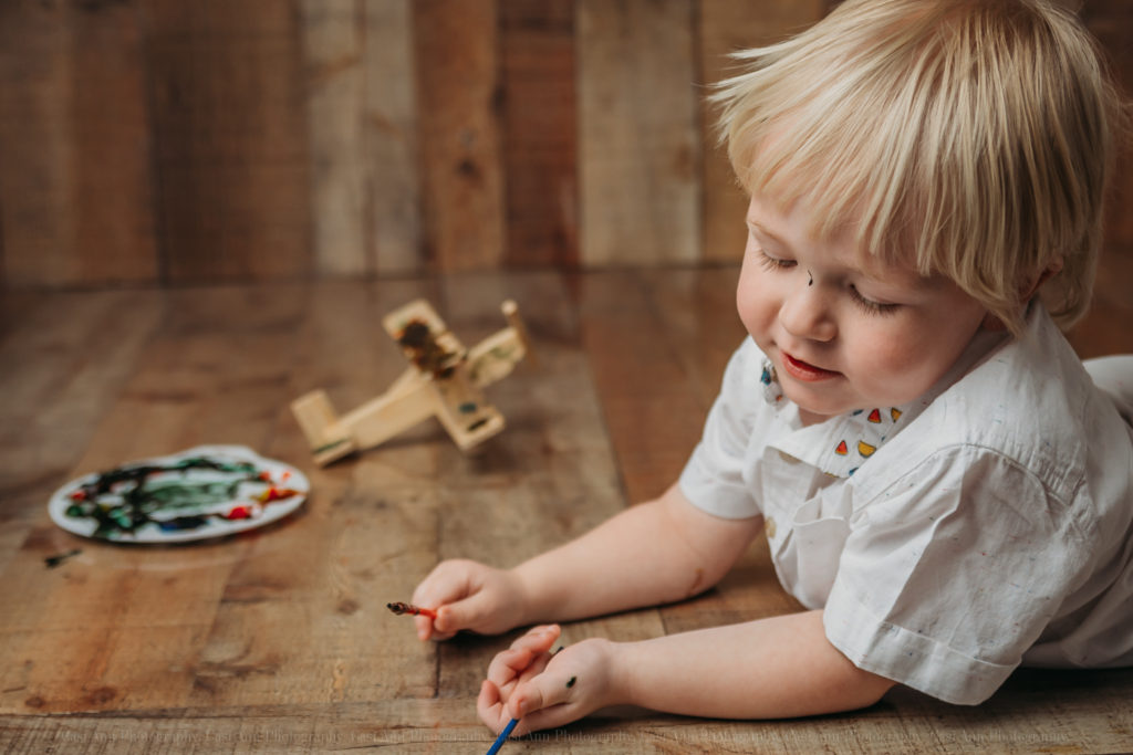 Toddler Lifestyle Photography-Casi Ann Photography-Illinois-IL-Ingleside-Lake County-Airplane-World Art Day-Arts-Crafts-Painting-Toddlers-Crafty-Photographer-Wood-Plane-Painted-studio-session
